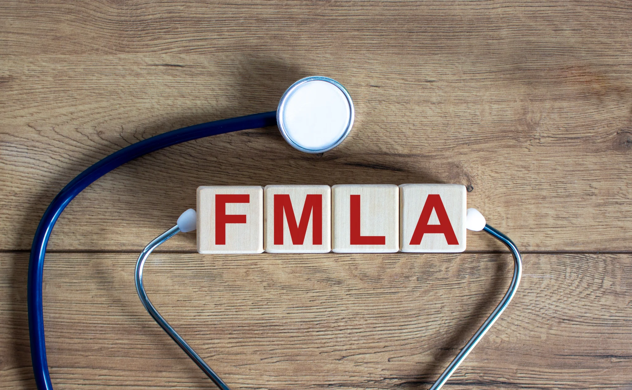 Concept word 'FMLA, family medical leave act' on cubes on a beautiful wooden background. Stethoscope. Copy space, medical concept.