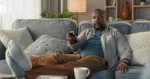 Man sitting on couch watching Dopesick on Hulu